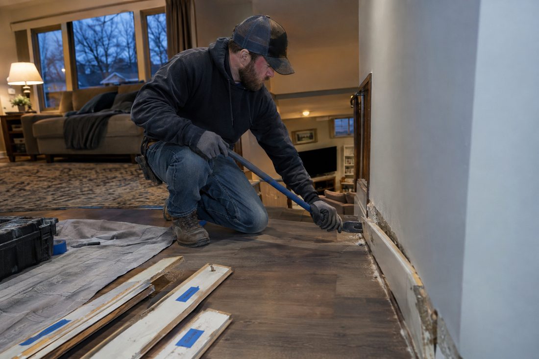 A technician removing baseboards with a pry bar and labeling them at a split-level home with a finished basement in the Missouri Northland in Kansas City, MO