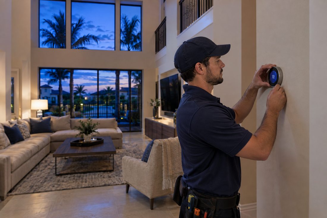 A smart thermostat being set up on a living room wall inside a two-story stucco home in a gated community in Palm Beach Gardens, FL